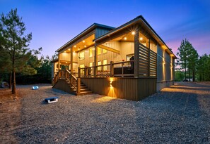 Une cabane en bois à deux étages, dotée d’un porche couvert et d’un escalier menant à l’étage supérieur.