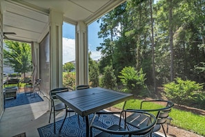 A covered outdoor patio with a table and chairs, surrounded by a forested area. - Stunning&Serene Golf Resort Condo (Calabash)