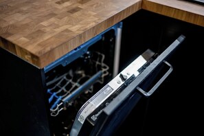 Eine Spülmaschine mit einer Holzausziehtafel darüber.