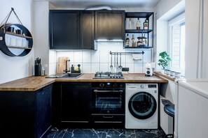 Eine kompakte Küche mit Einbauofen, Waschmaschine und einer Arbeitsplatte mit Spüle.