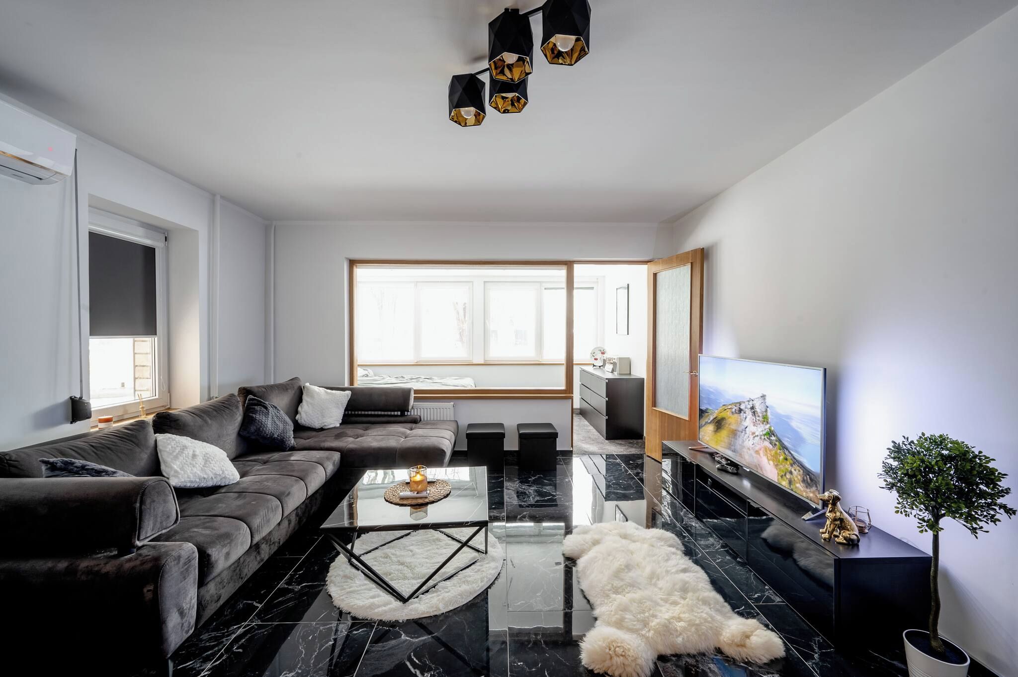A modern living room with a sectional sofa, a coffee table, a TV, and a fireplace.