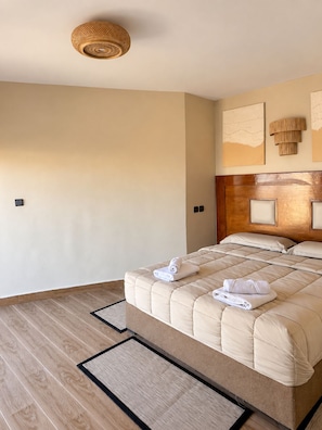 A hotel room with a large bed, a wooden headboard, and a woven ceiling light fixture.