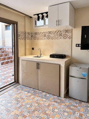 A compact kitchen with a sink, cabinets, and a small refrigerator.