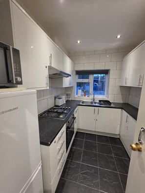 A compact kitchen with white cabinets, a black countertop, a gas stove, and a built-in oven. - Spacious house in Greater London
5 bedrooms 5 bathrooms (London)