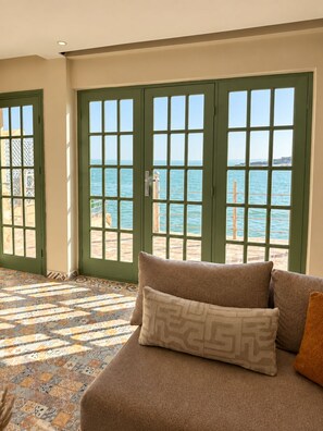 A room with a large window, a patterned floor, and a sofa with cushions.