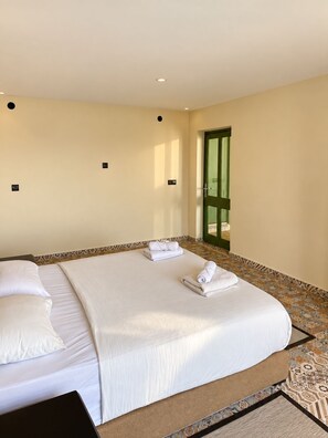 Een hotelkamer met twee bedden, een groene deur en een betegelde vloer.