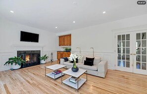 Living room with hardwood floors, a lit fireplace, and comfortable seating. - Hamptons Retreat | Private Pool & 3BR Escape (East Quogue)