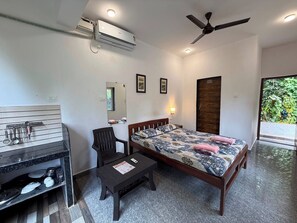 Un dormitorio con cama, escritorio, silla, ventilador de techo y unidad de aire acondicionado.