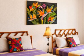 A hotel room with two beds, a nightstand, a lamp, and a floral painting on the wall. - Above the Gardens. Beyond Expectations - Villa Rosamaria, Pet-Friendly (Manzanillo)