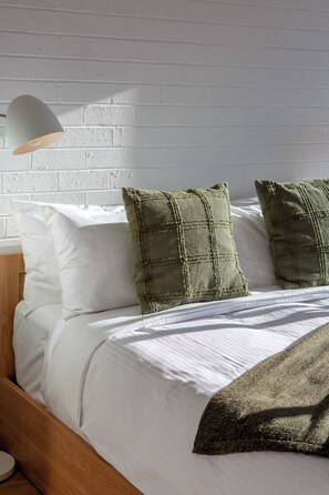 A neatly made bed with white linens and two green textured pillows. - Sydney Panorama Iconic City Views and Rooftop Pool (Potts Point)