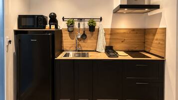 Una cocina compacta con un refrigerador negro, un microondas, un fregadero y una estufa.