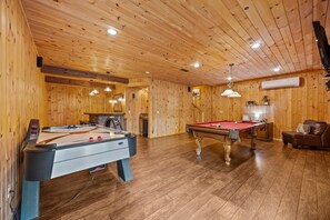 Ein Zimmer mit Holzboden, Billardtisch, Kamin und Pooltisch.