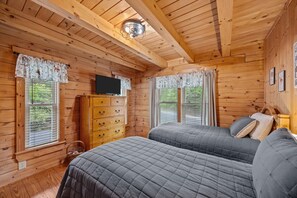 Ein Holzhütten-Zimmer mit zwei Betten, einem Schminktisch und einem Fernseher.