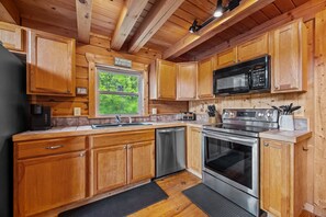 Une cuisine dotée de meubles en bois, d’un lave-vaisselle en acier inoxydable, d’un four à micro-ondes et d’un four traditionnel.