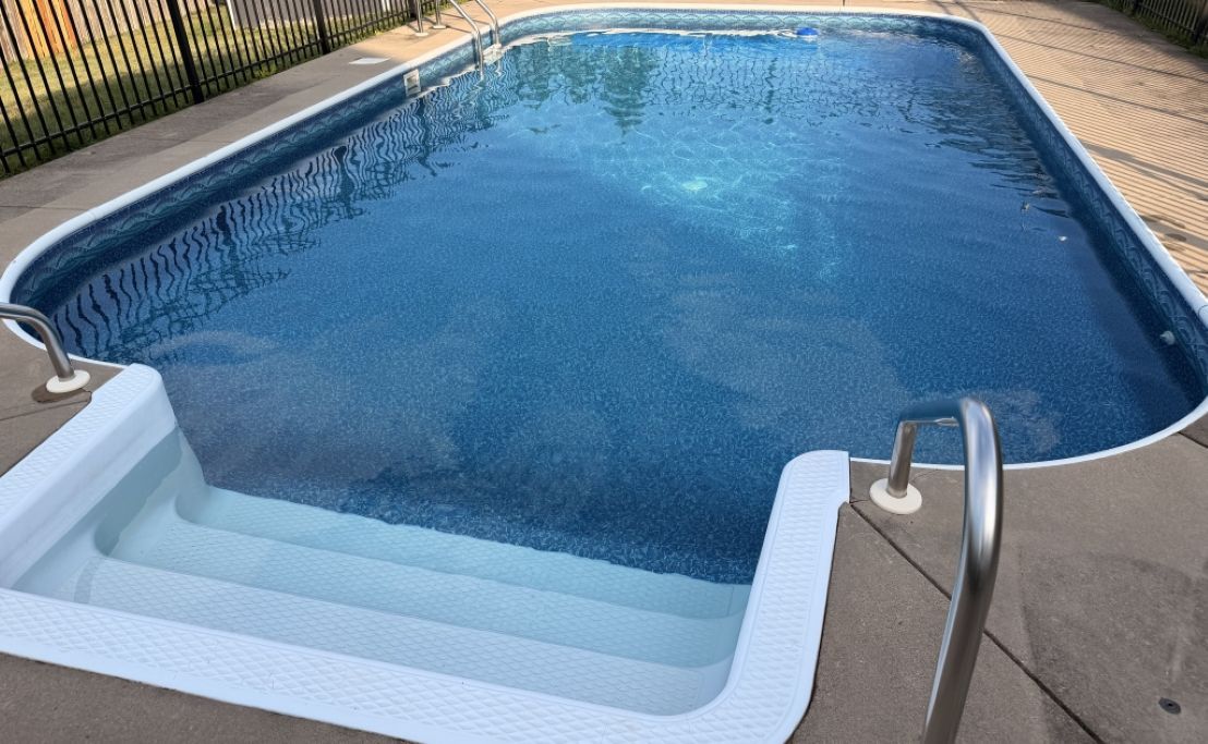 Ein rechteckiger Swimmingpool mit klarem, blauem Wasser, umgeben von einer Fliesenveranda.