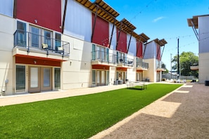 A multi-story building with balconies, a grassy courtyard, and outdoor seating. - San Antonio Ranch Loft | 2BR/2BA Garage + Pool (San Antonio)