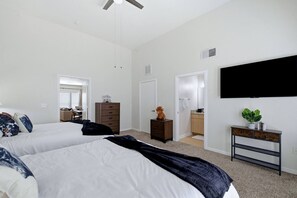 A hotel room with two beds, a dresser, a television, and a plant. - San Antonio Ranch Loft | 2BR/2BA Garage + Pool (San Antonio)