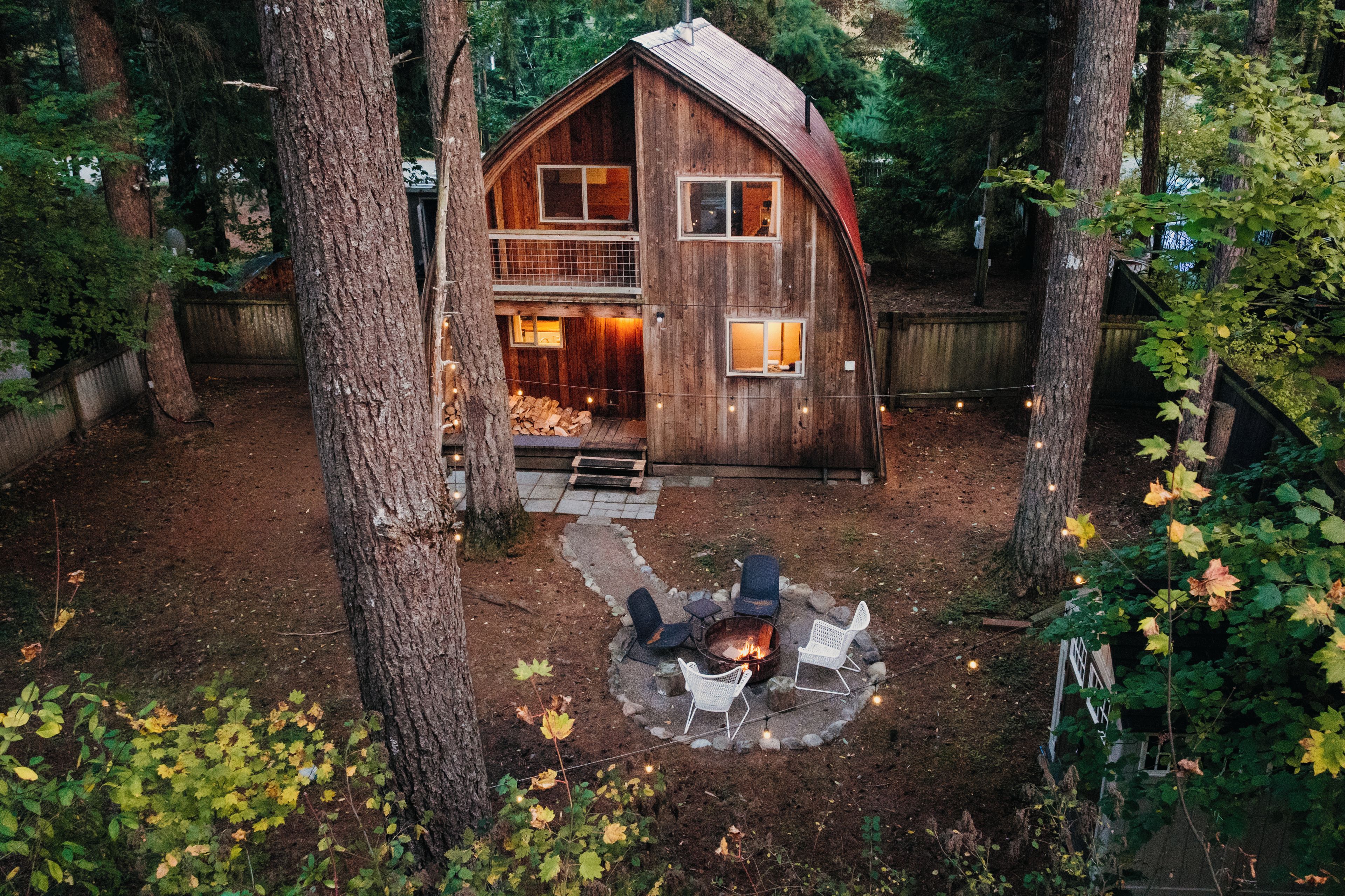 A wooden cabin with a fireplace, outdoor seating, and a stone pathway leading to the entrance.