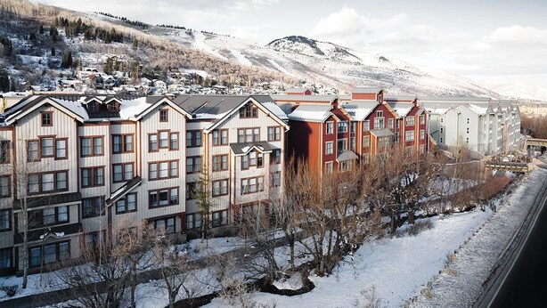 Una serie di edifici a più piani con stili architettonici diversi, in un paesaggio innevato con montagne sullo sfondo.