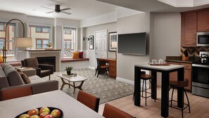 A modern living room with a fireplace, a dining area with apples, a kitchen with a microwave, and a TV mounted on the wall. - Marriott's Summit Watch is an ideal place to enjoy this cozy retreat. (Park City)