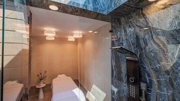 Ein modernes Badezimmer mit Marmorwand, einer Duschkabine aus Glas, einer weißen Badewanne und einem kleinen Tischchen mit einer Vase.