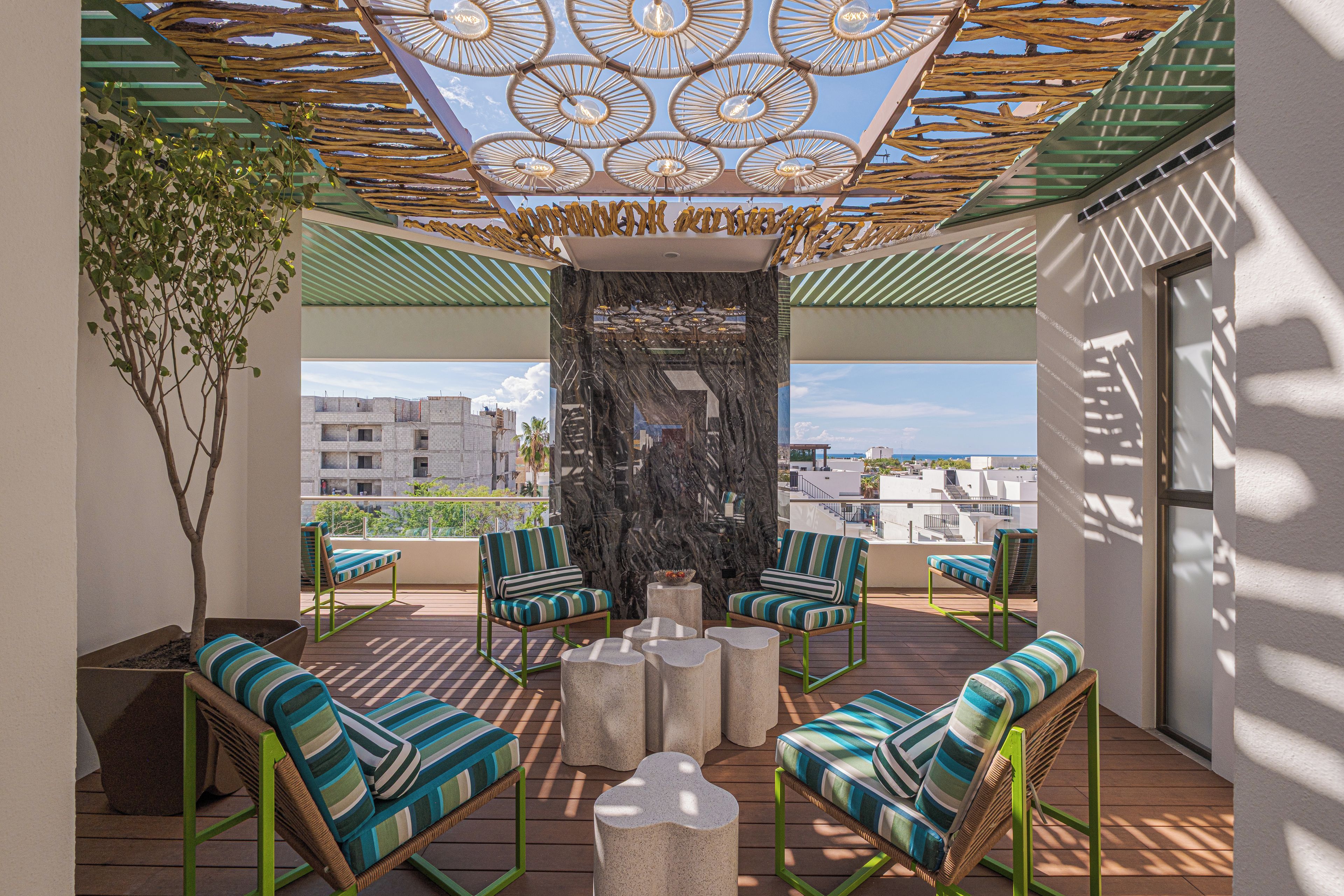 A rooftop terrace with outdoor seating, a decorative wall, and a view of the cityscape.
