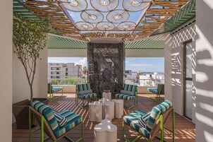 Una terraza en la azotea con mobiliario exterior, un muro decorativo y vistas de la ciudad.