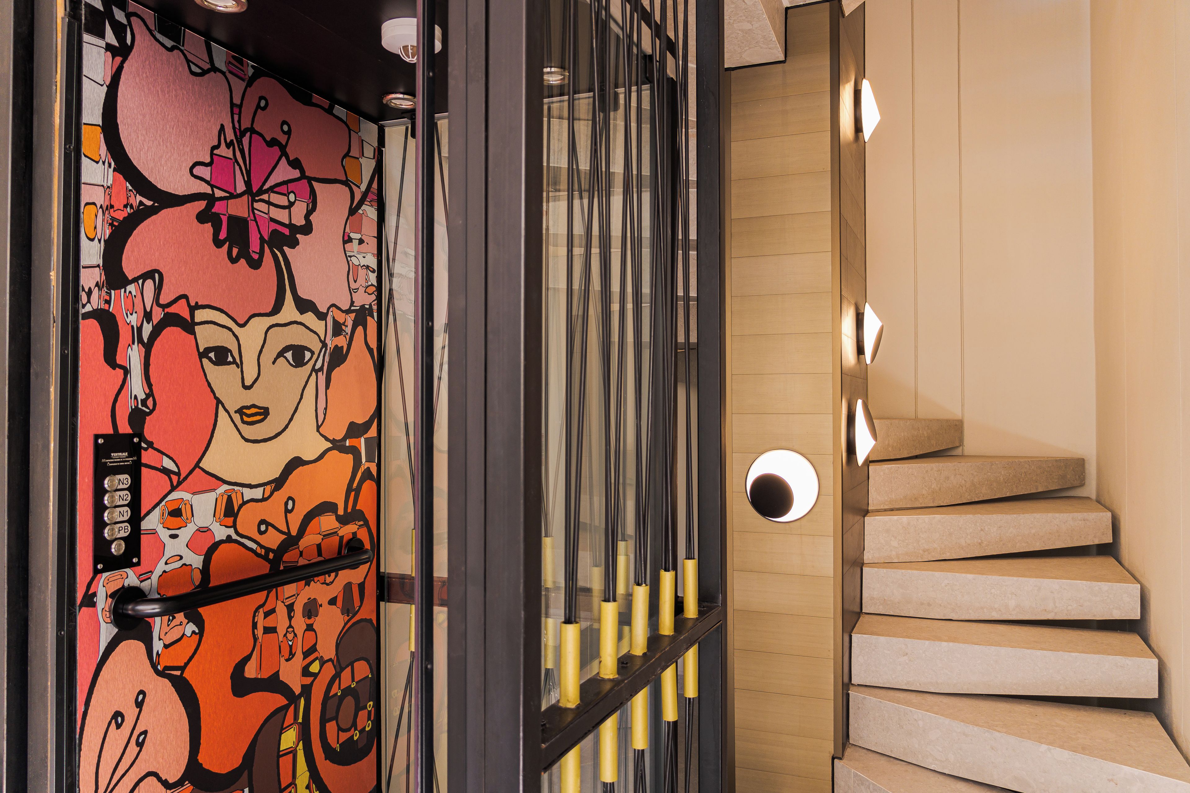 Una escalera moderna con diseño minimalista, una pared decorativa con arte abstracto y un panel de control con botones.