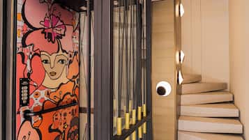 Una escalera moderna con diseño minimalista, una pared decorativa con arte abstracto y un panel de control con botones.
