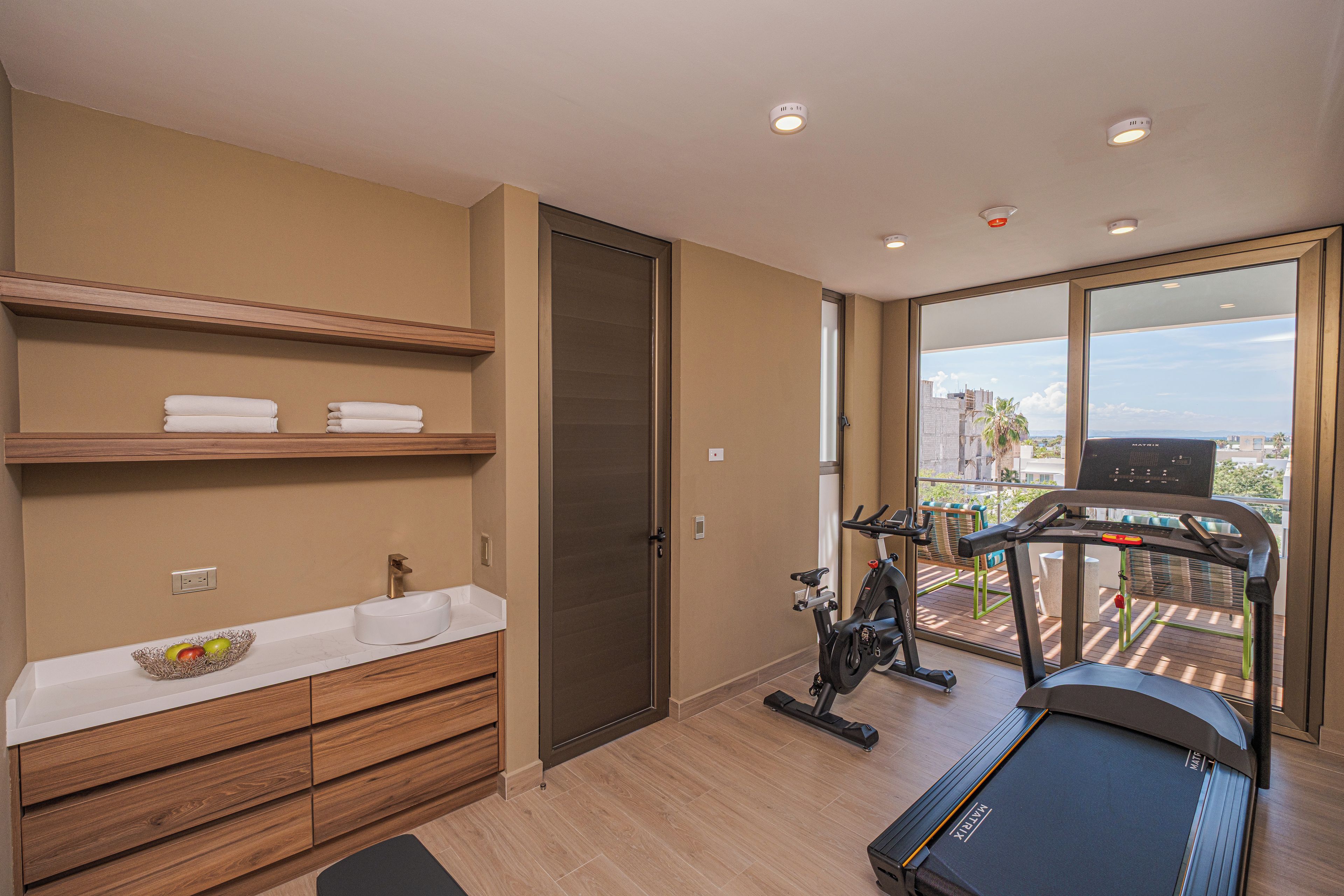 Un baño moderno con un mueble de tocador de madera, un lavamanos blanco y un perchero para toallas.