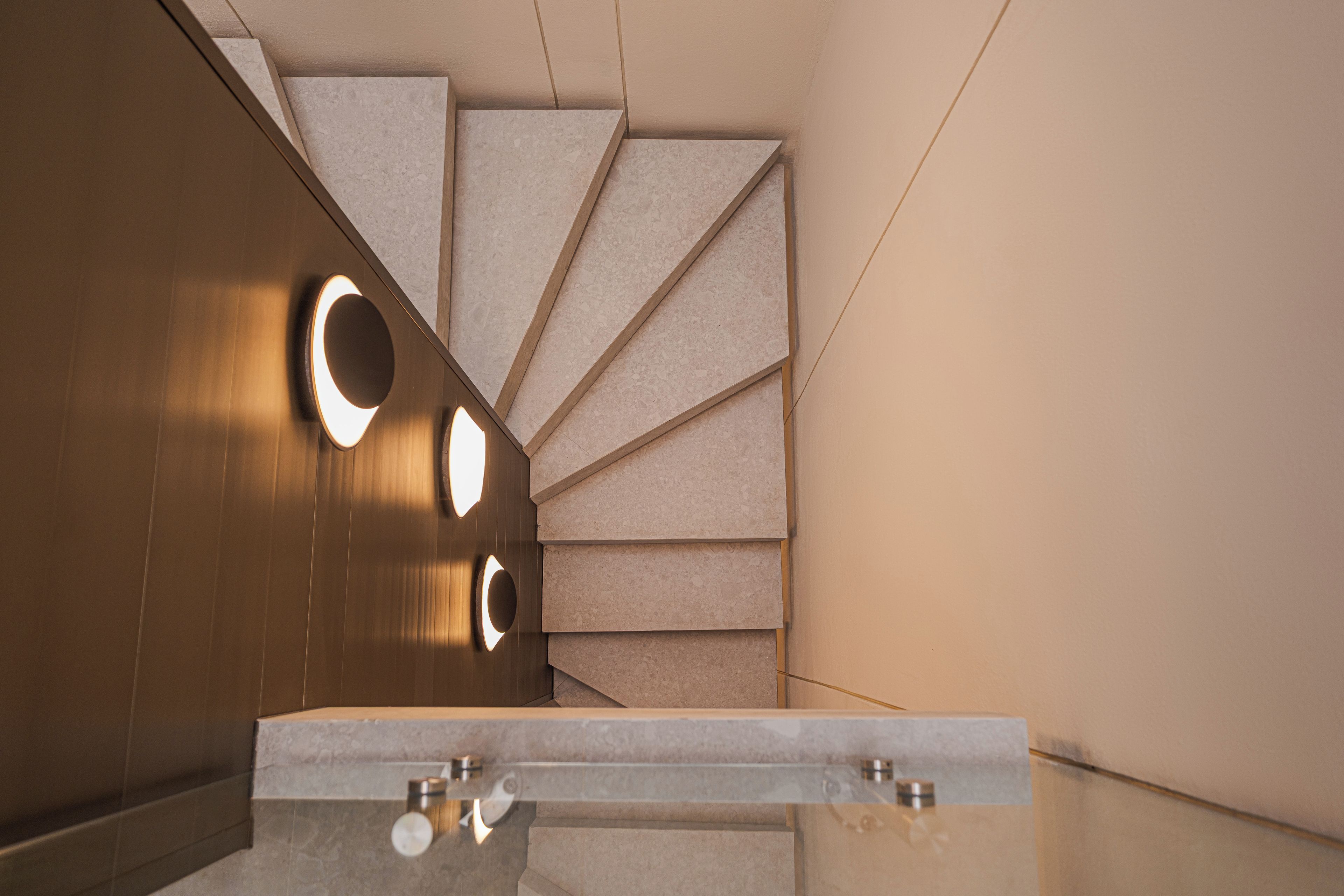 Un baño moderno con un lavabo de mármol, tocador de madera y diseño geométrico en la pared.