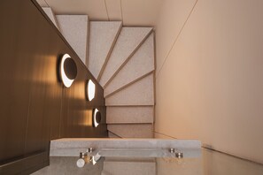 A modern bathroom with a marble sink, a wooden vanity, and a geometric wall design. - Hotel Flamingos (La Paz)
