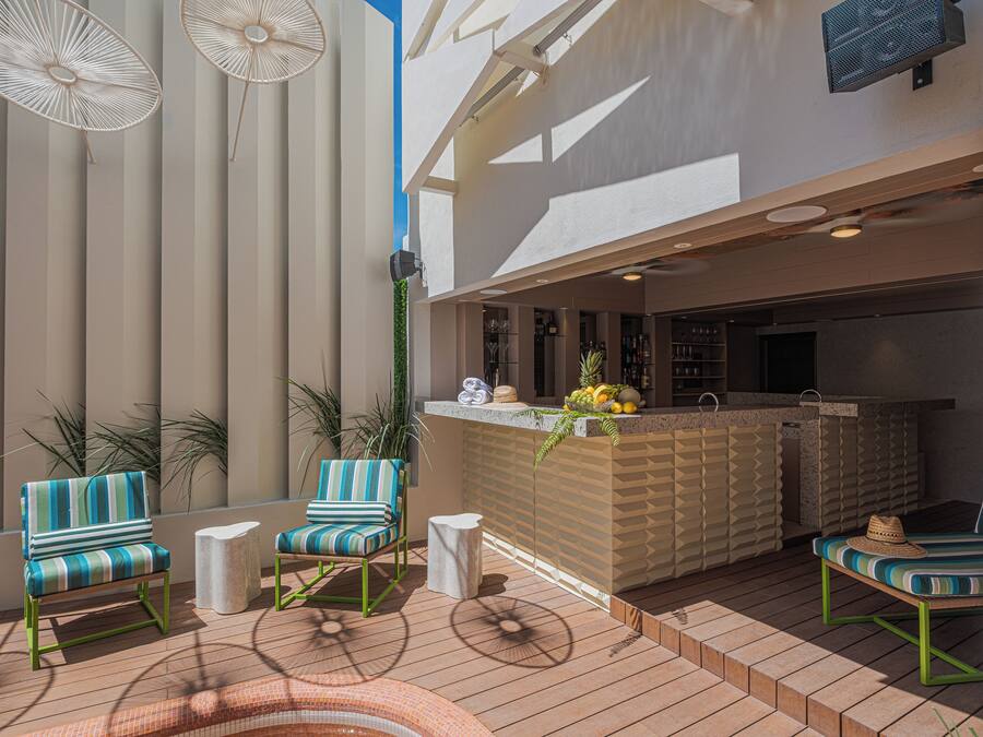 Een terras met twee gestreepte stoelen, een bijzettafeltje en een bar met een presentatie van fruit.