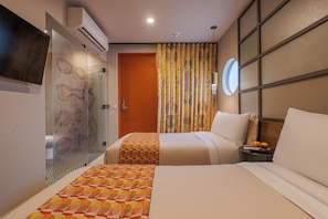 Habitación de hotel con dos camas, un televisor, una ventana con cortinas y un aire acondicionado instalado en la pared.