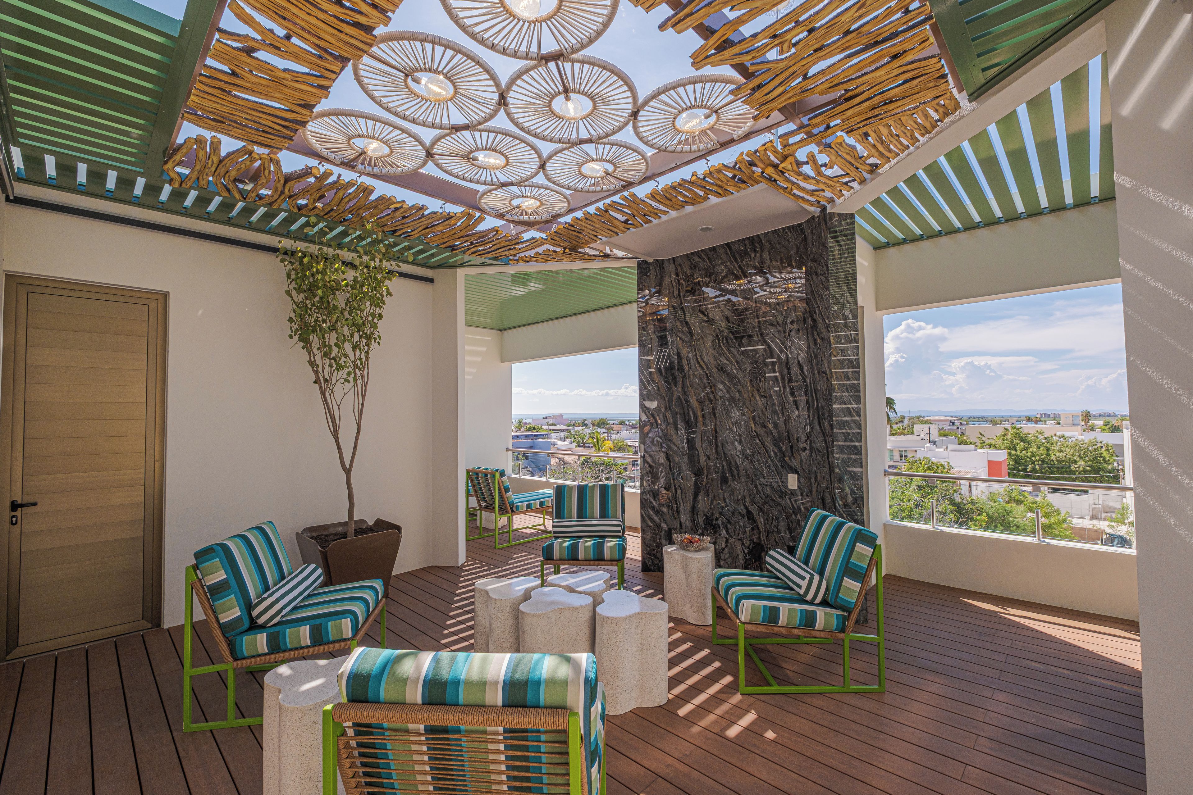 A balcony with wicker furniture, a potted plant, and a view of the cityscape.