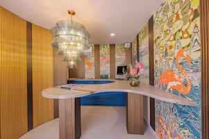 Un interior moderno con un banco curvo, una lámpara decorativa y colorida obra de arte abstracta en la pared.