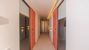 Un pasillo con puertas a ambos lados, piso alfombrado y luces fijadas en la pared.