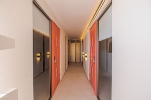 Un pasillo con puertas a ambos lados, piso alfombrado y luces fijadas en la pared.
