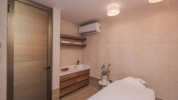 Un baño moderno con una puerta de madera, un lavamanos, un perchero para toallas y un aire acondicionado de pared.