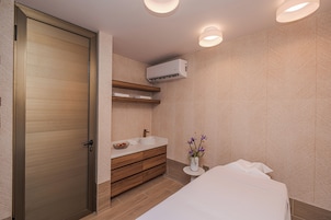 Un baño moderno con una puerta de madera, un lavamanos, un perchero para toallas y un aire acondicionado de pared.