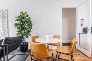 Un espace repas moderne comprenant une table ronde, quatre chaises, une plante en pot et un coin cuisine équipé d’un four à micro-ondes.