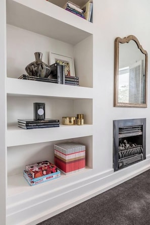 A bookshelf with books, decorative items, and a mirror. - By the Bay Elegance A Laid back Urban Retreat (Brighton East)