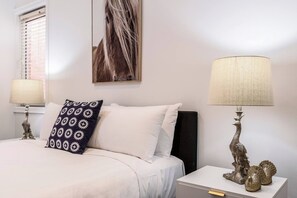 Una camera d'albergo con un letto, due lampade ai lati, un elemento decorativo a parete e un comodino con lampada.