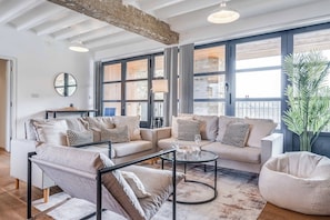 A modern living room with a sofa set, a coffee table, and a large window with a view. - Luxe Penthouse with Balcony & Parking (London)