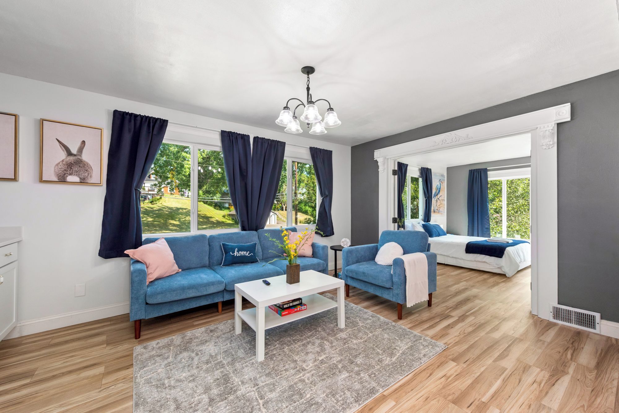 A modern living room with two sofas, a coffee table, and a chandelier.