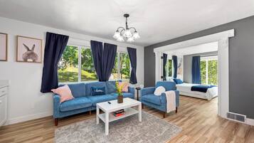 A modern living room with two sofas, a coffee table, and a chandelier.