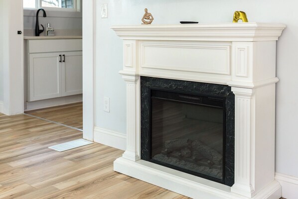 A white fireplace with a black marble surround, a white mantel, and a small statue on top.