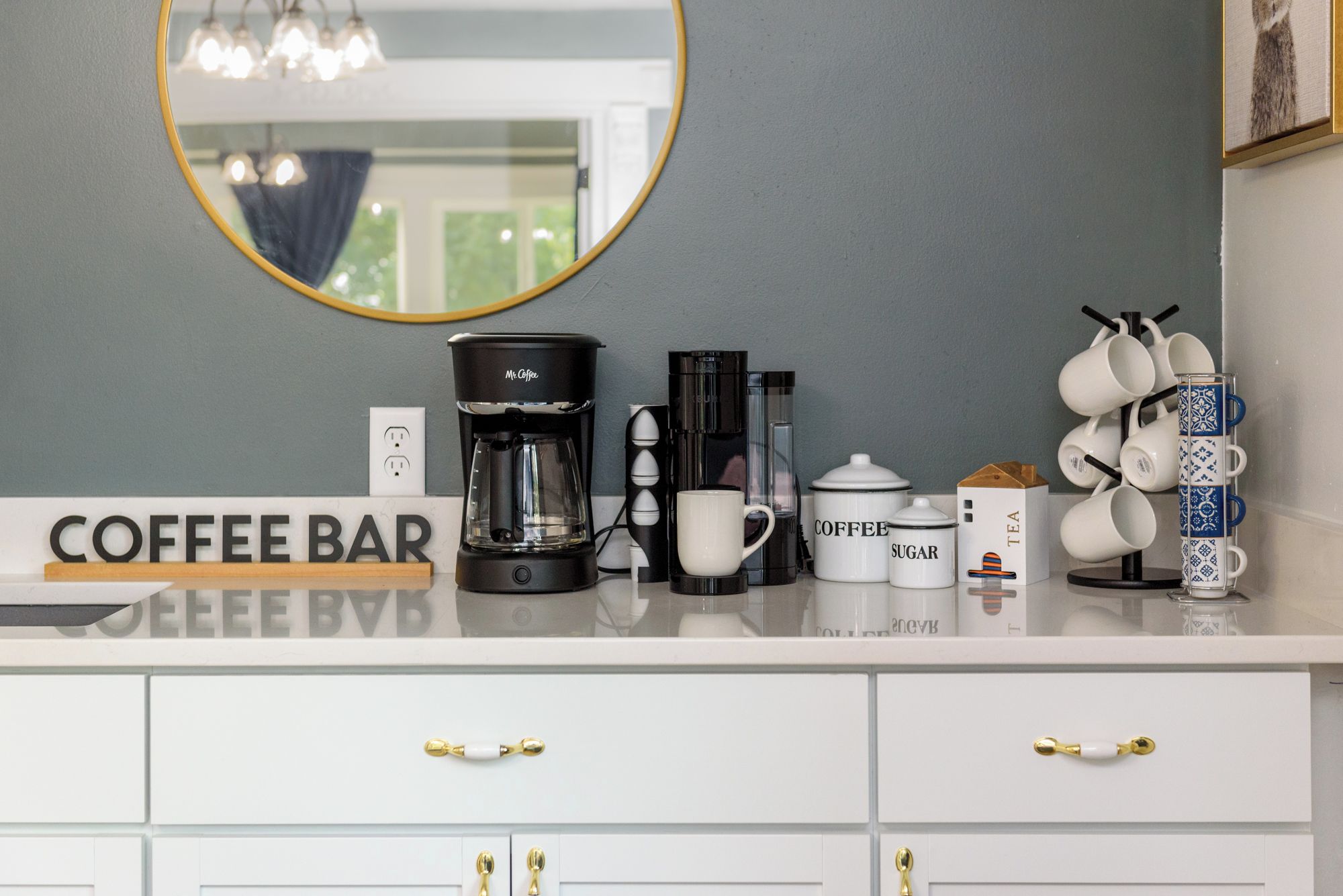 A coffee bar setup with a coffee maker, cups, sugar, and tea.