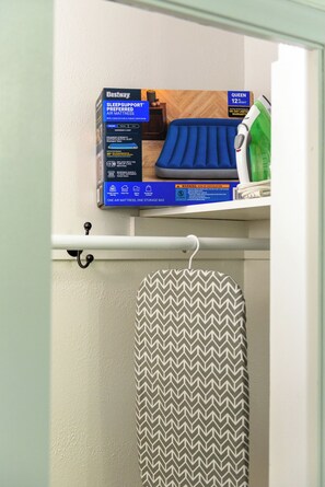 A Bestway Queen 12-inch height air mattress with a 180-day limited warranty, placed on a shelf above a towel rack with a patterned towel. - Lakefront 5BR Retreat on Lake Phalen-Sleeps 14-Fire Pit & Workspace (Saint Paul)