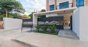 A modern building with a garage entrance, a small garden with palm trees, and a clear sky. - Two-Bedroom Quiet Stay with Rooftop Pool&CoWorking (Fernando de la Mora)